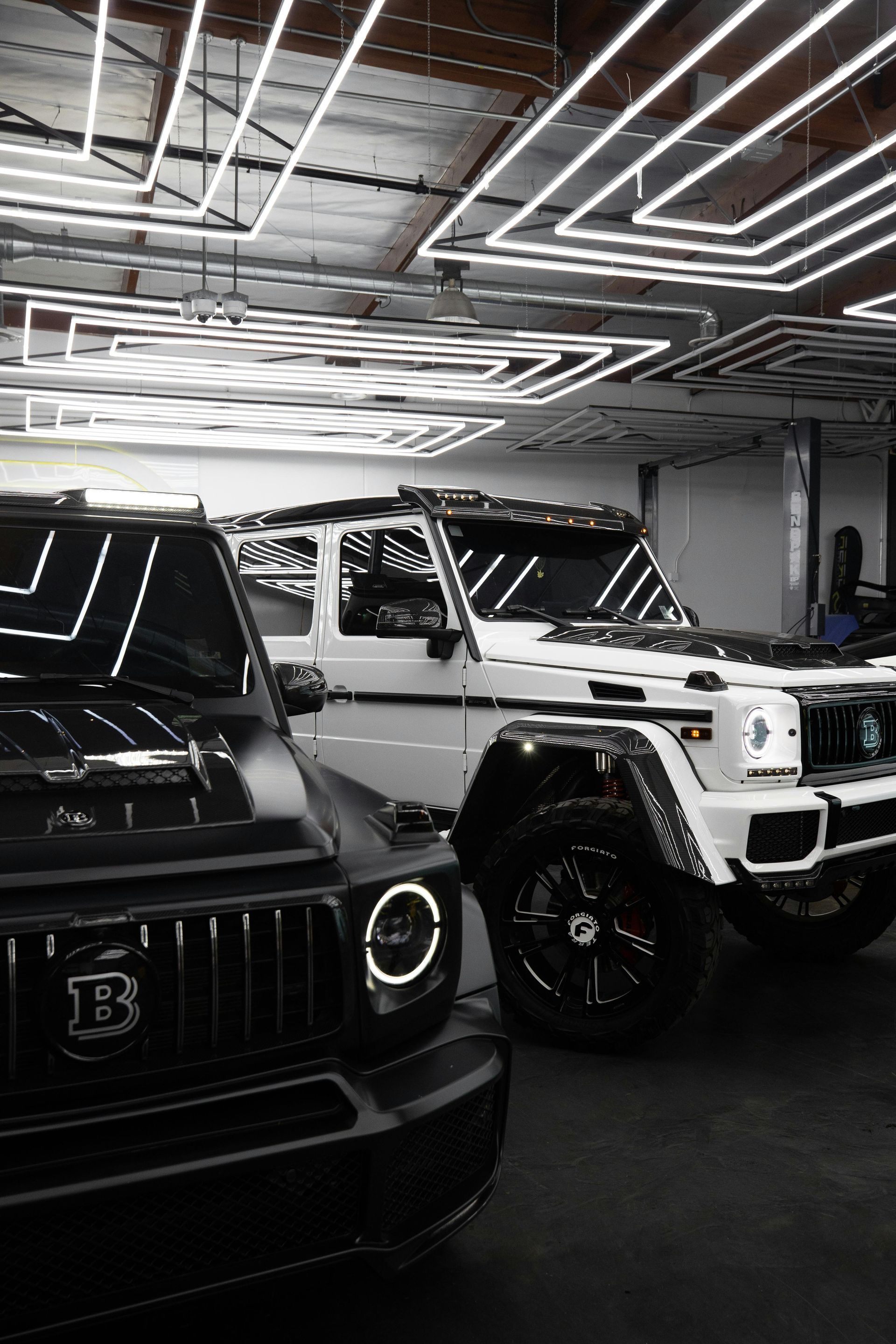 A row of black and white cars are parked in a garage.