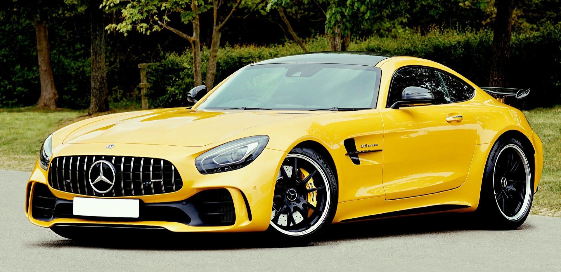 A yellow mercedes amg gt r is parked on the side of the road.