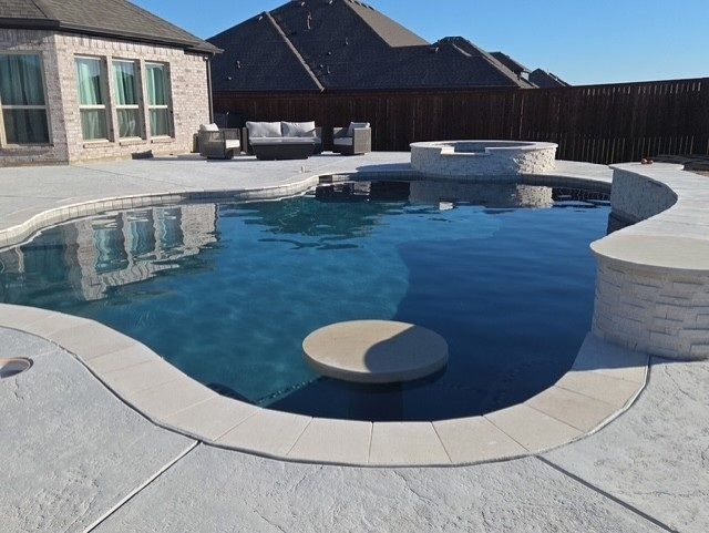 Pool with a built-in bar and fire pit in a backyard with a house.