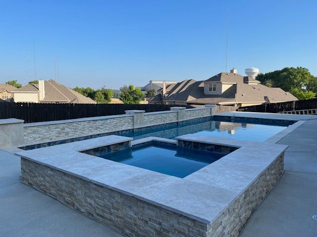 Pool with stacked stone walls and water, against a clear sky.