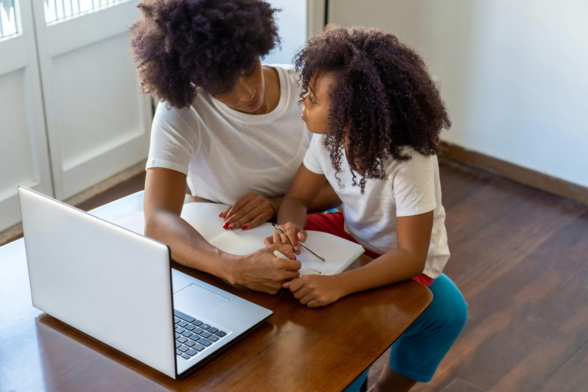 Adult and child using a tablet together on a couch, with the adult gently guiding the child.
