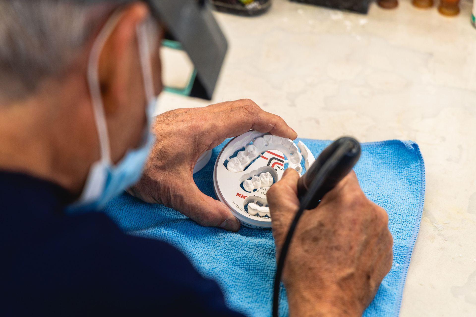 An image of a lab technician drilling new artificial teeth