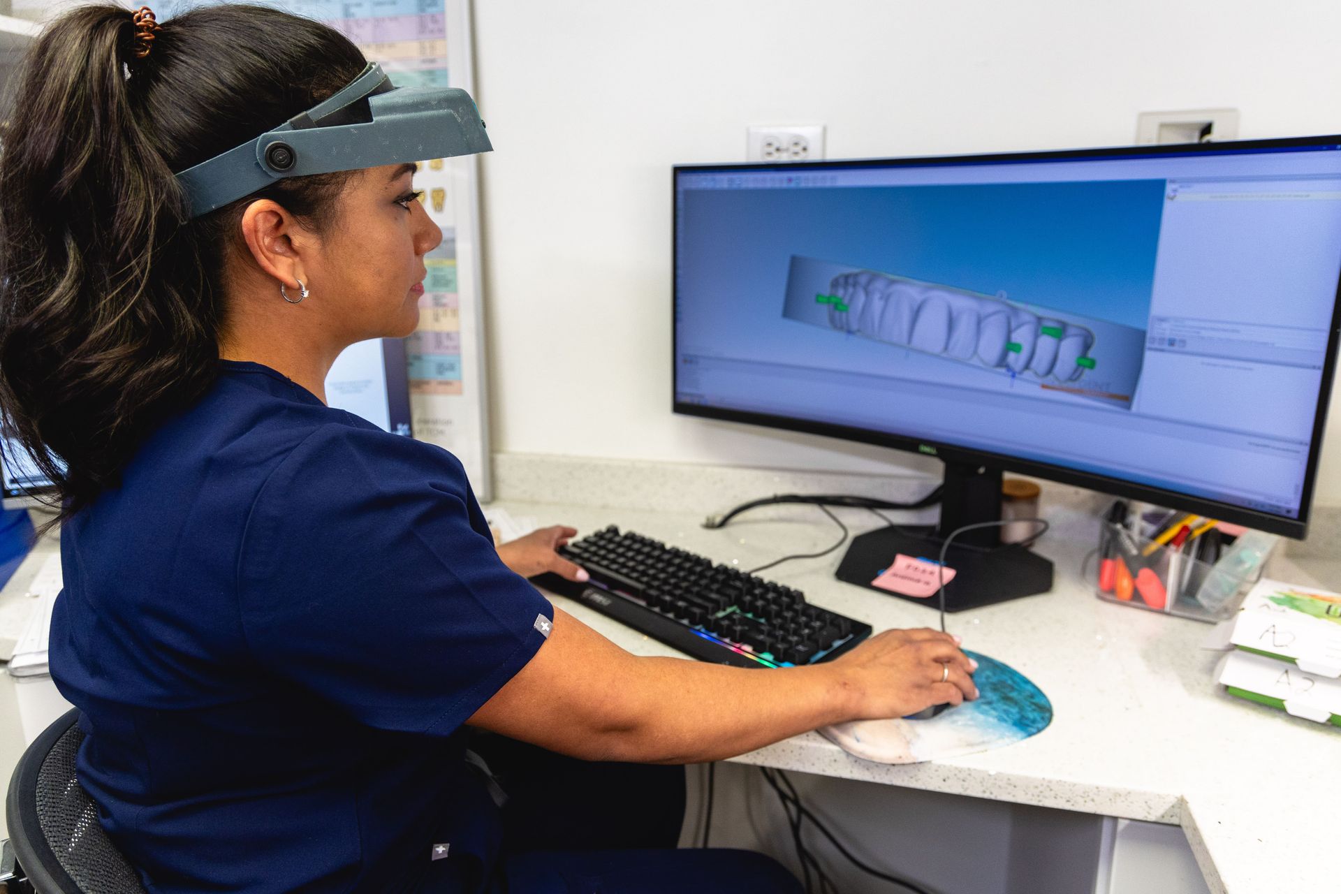 An image of a lab technician looking at a mockup of new teeth on a computer