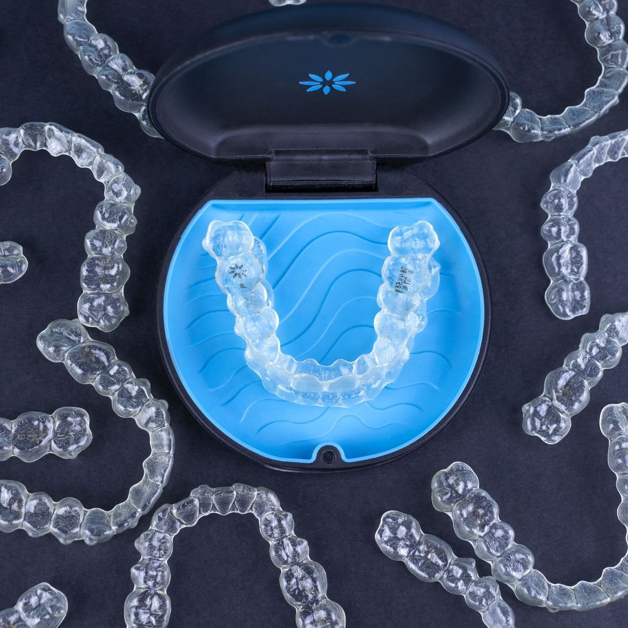 An image of an Invisalign® case surrounded by Invisalign® aligners