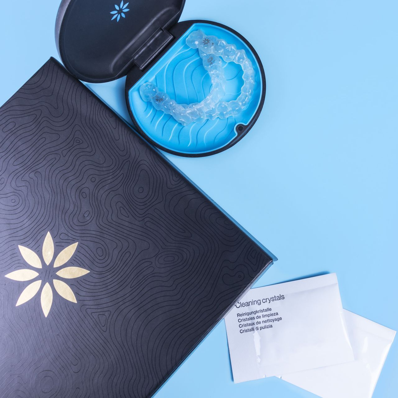 An image of an Invisalign® case with aligners, Invisalign® packaging, and cleaning crystals