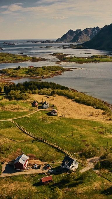Green fields with homes nestled along a coastline; mountains and sea in the background.