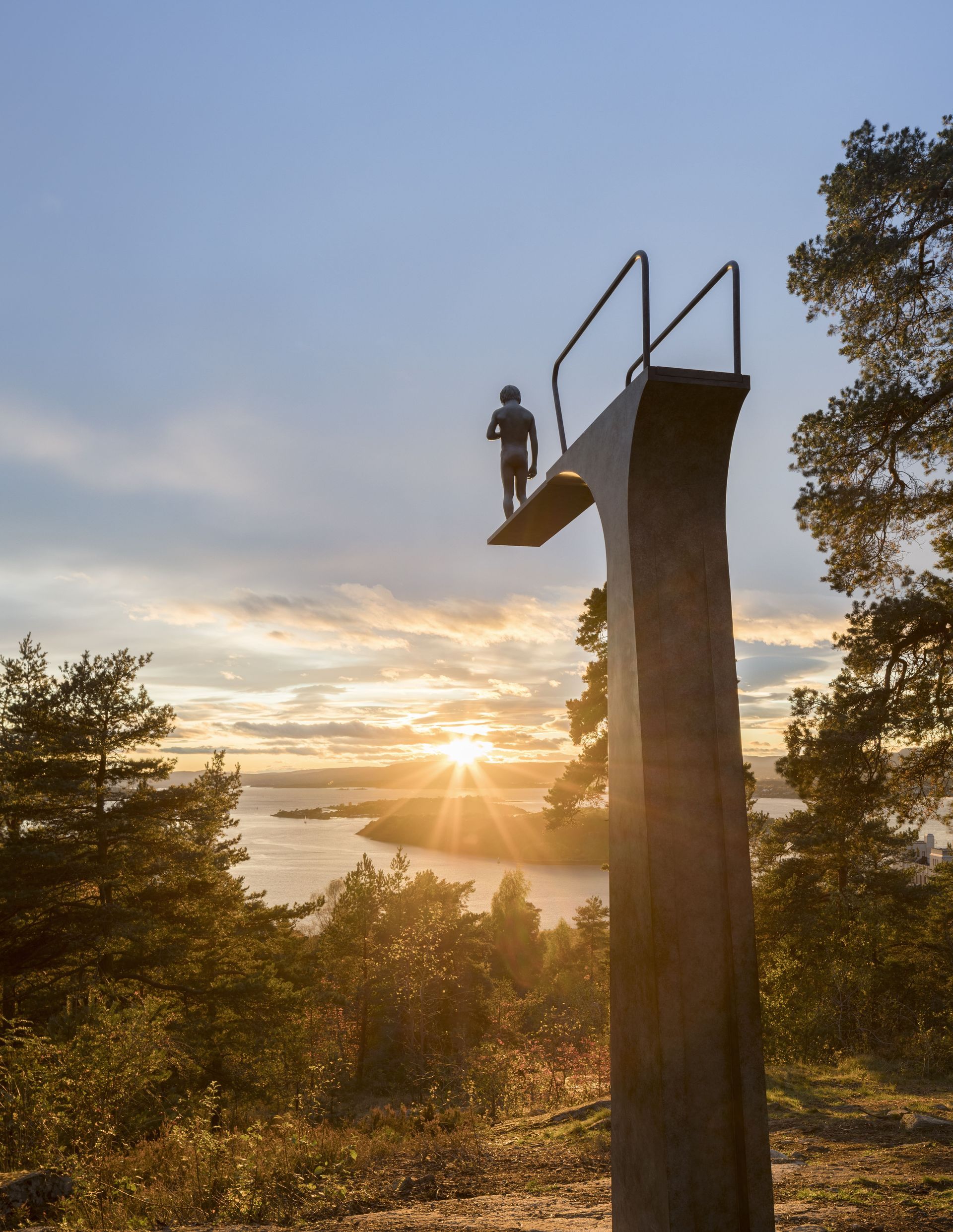Person on a diving board, silhouetted against a sunset over a body of water, trees in foreground.
Elmgreen & Dragset; Dilemma, 2017 ÓElmgreen & Dragset/BONO
Photo: Florian Holzherr
