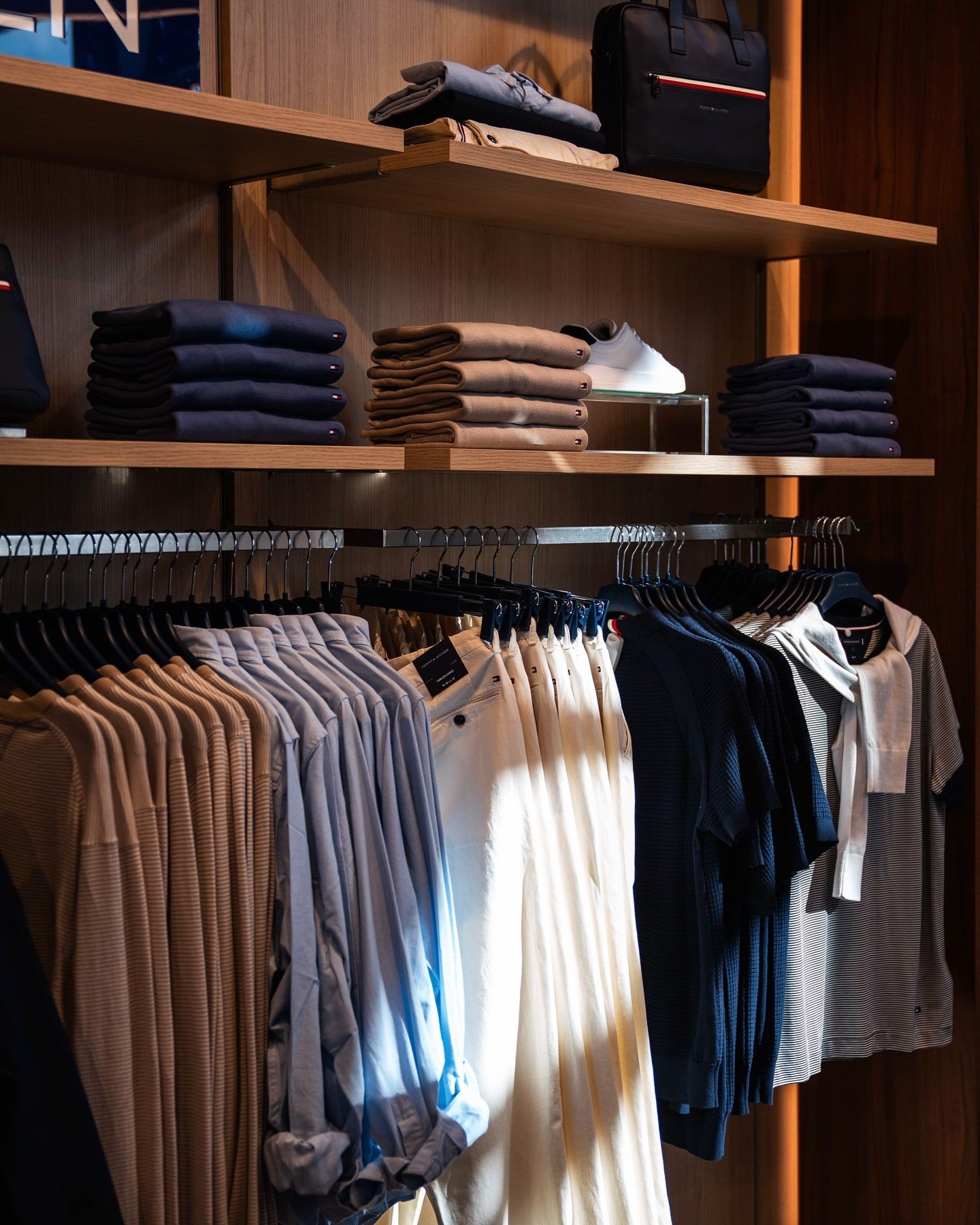Clothing store display with folded and hanging clothes in neutral tones.