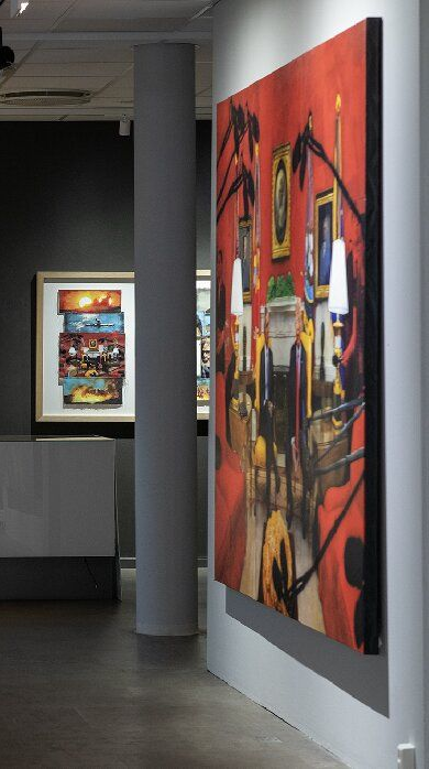 Ship figureheads of women in different colors displayed on a white wall in an art gallery.