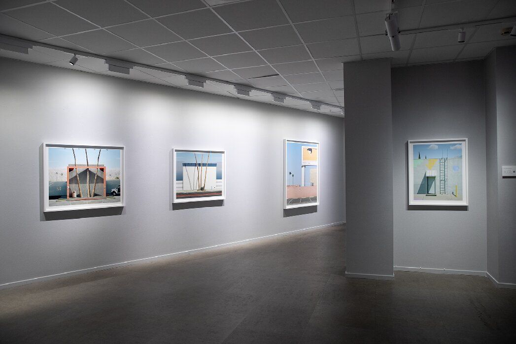 An interior view with a ship's wheel, telescope, and a window overlooking a cityscape at dusk.