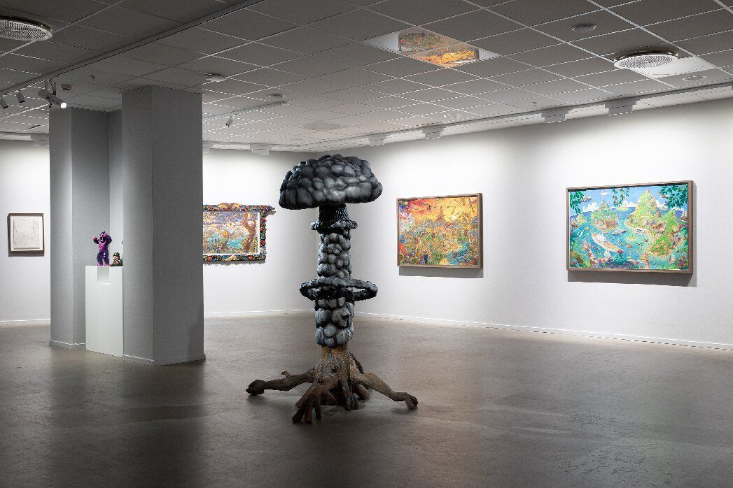 Model ship and maritime paintings displayed in a glass case.