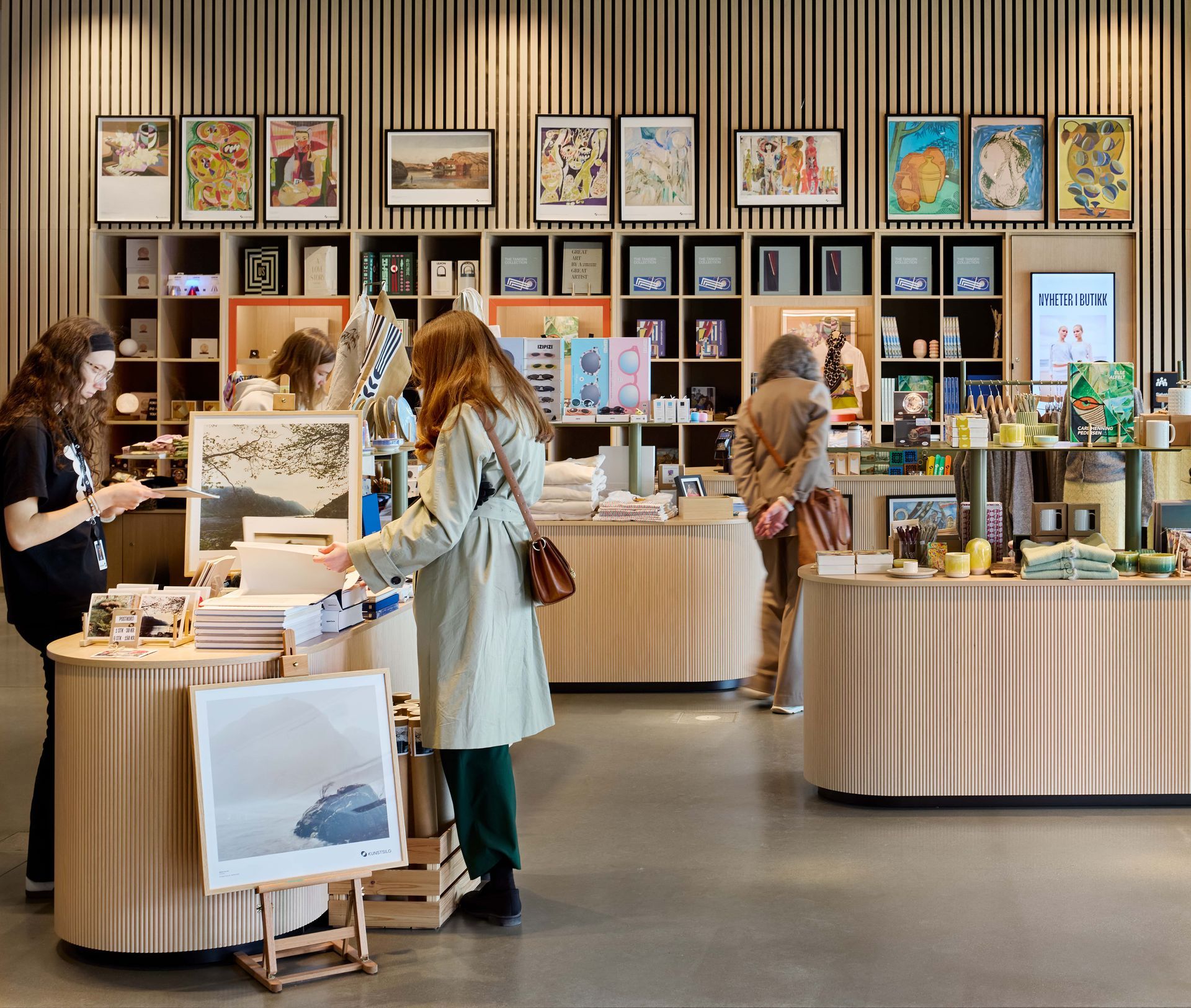 People browsing a museum gift shop with art prints, books, and souvenirs on display.