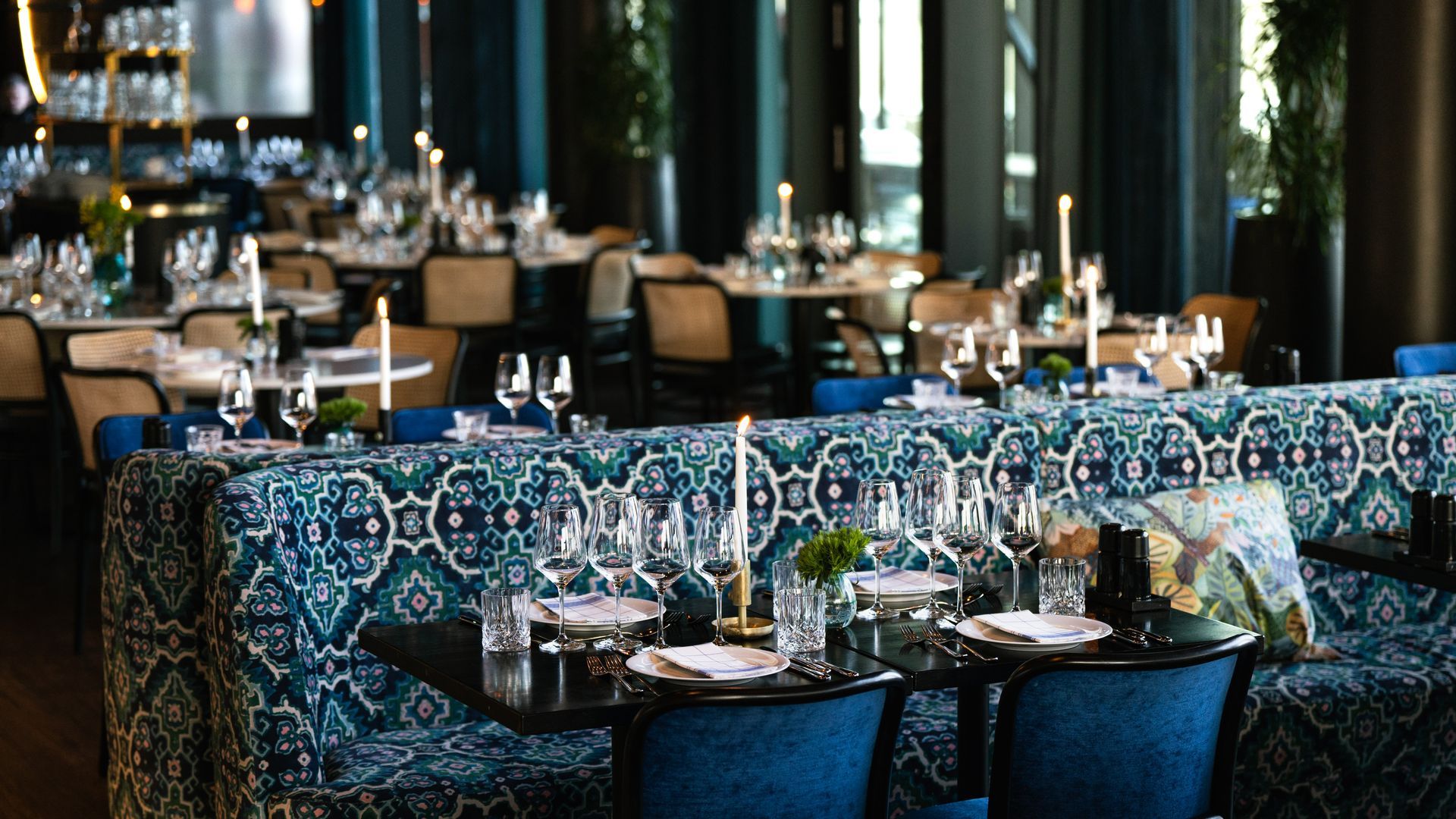 Outdoor cafe with people, building, mountain in background at sunset.