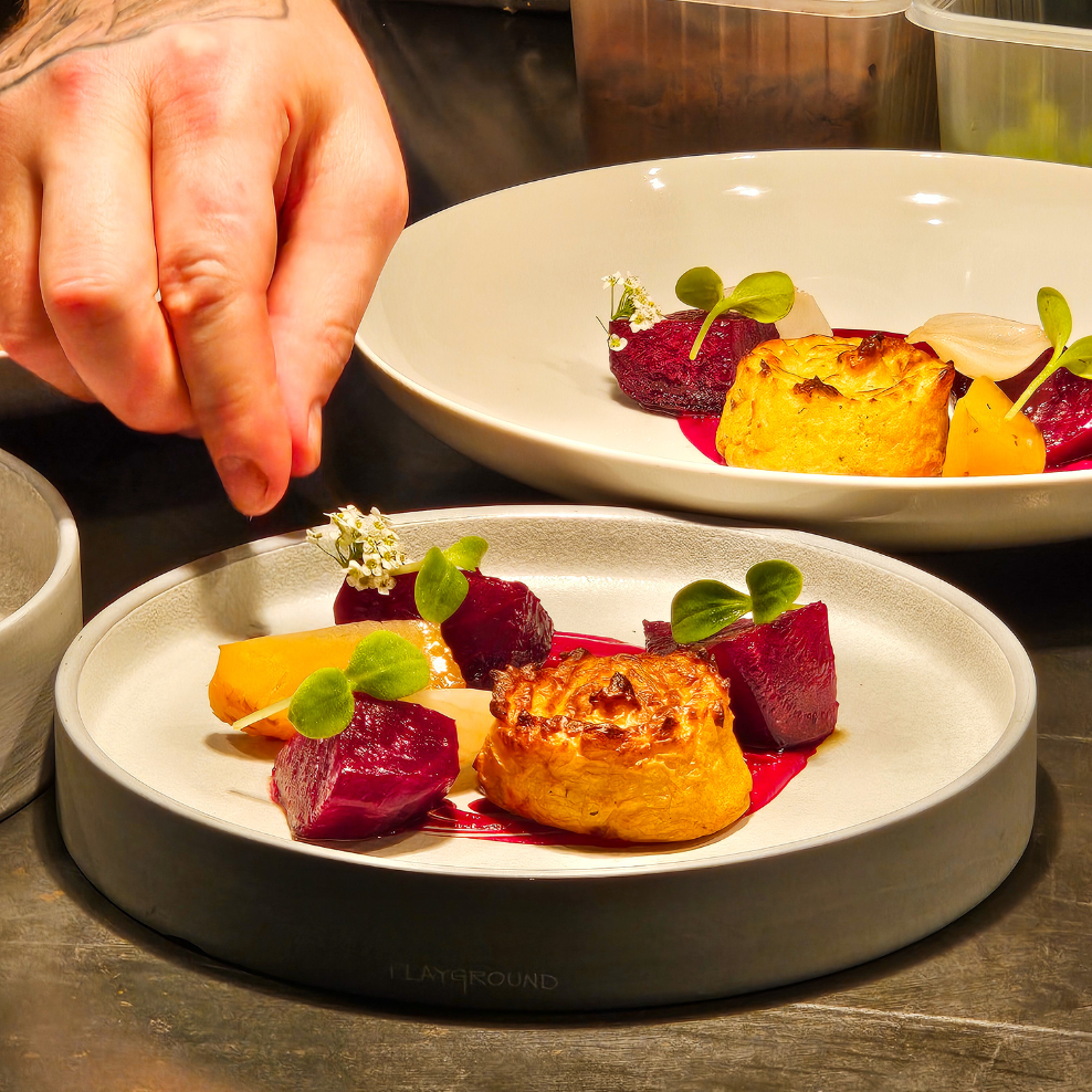 Oysters on a blue and white patterned plate with rock salt and lemon. One oyster is topped with green sauce.