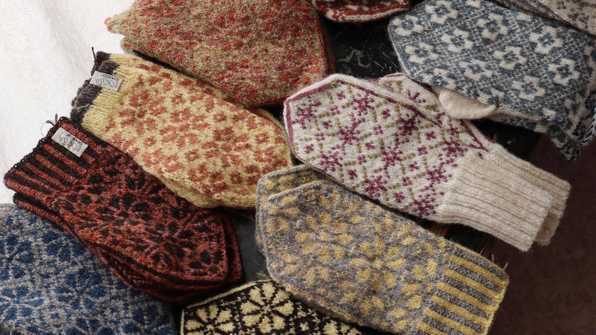 Pile of knitted mittens with various colorful patterns.