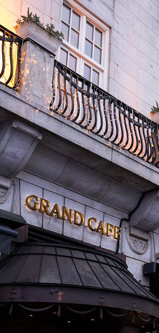 Exterior of the Grand Café. White building with arched windows, balconies, and gold lettering.