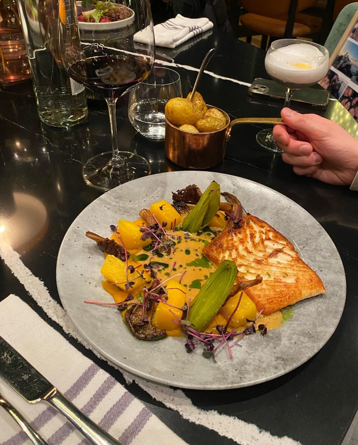 Oysters on a blue and white patterned plate with rock salt and lemon. One oyster is topped with green sauce.