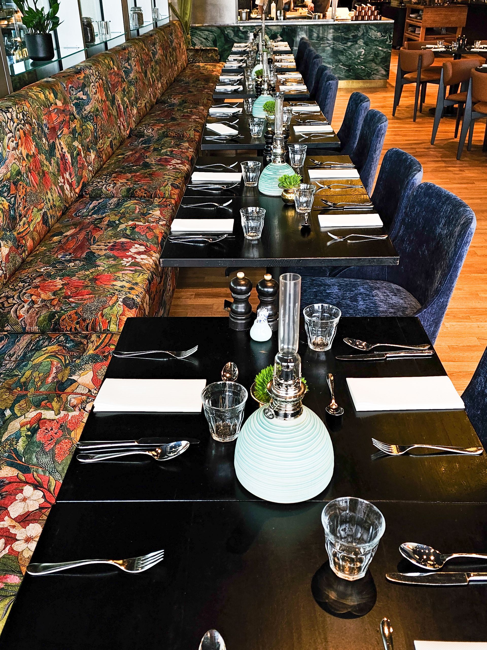 Outdoor cafe with people, building, mountain in background at sunset.