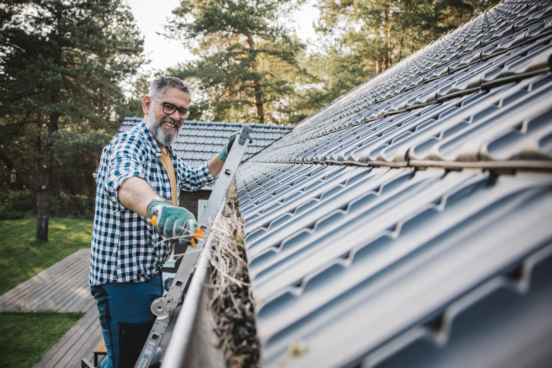 A man cleaning leaves from the guttering of the house