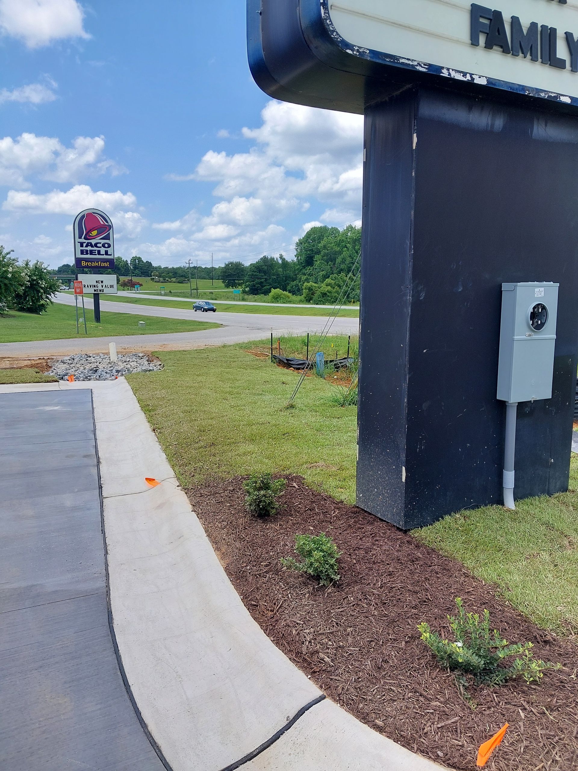 Sign for a family restaurant with a curb and landscaping in front. A second sign is visible in the distance.