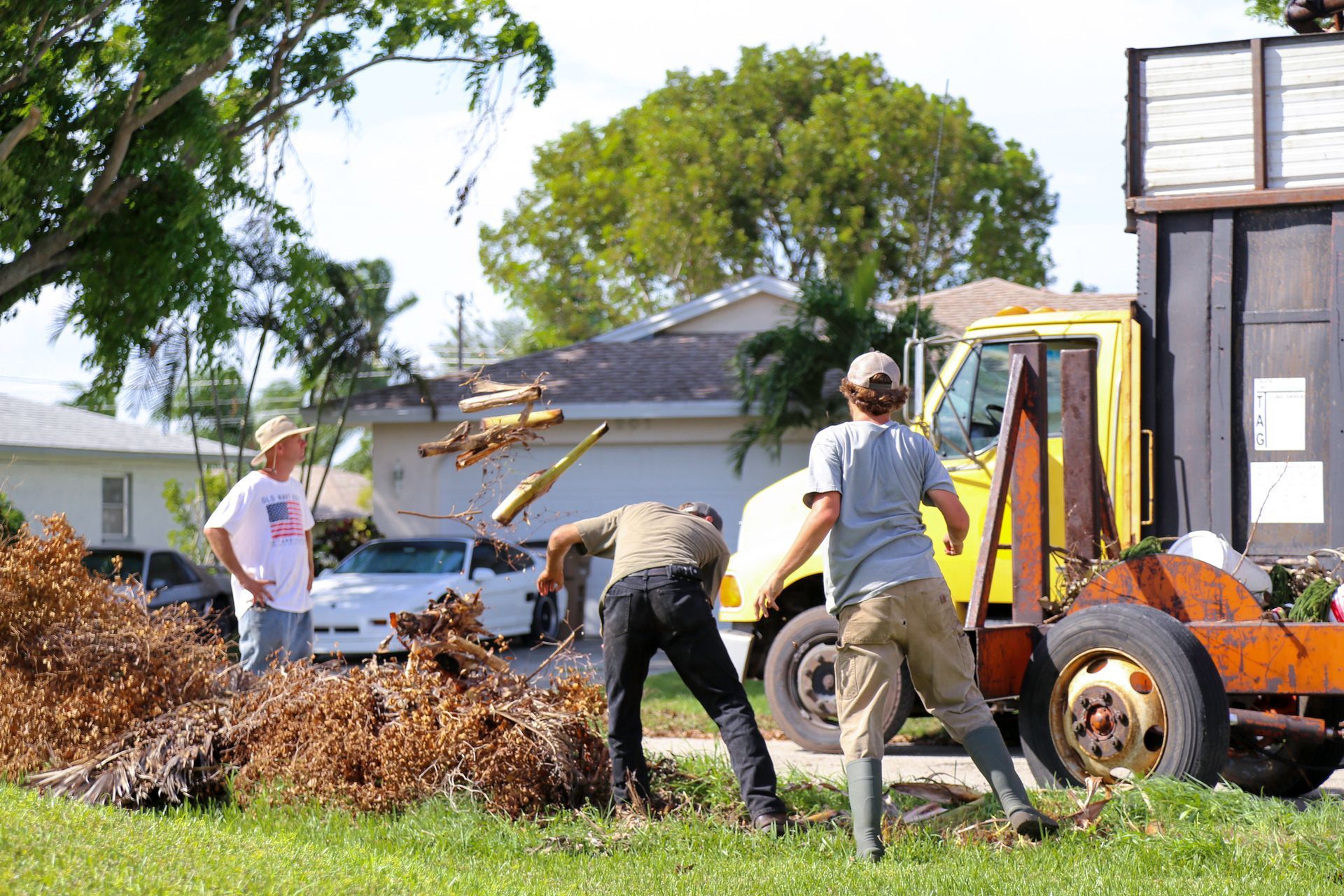 Contractors cleaning residential storm damage debris after natural disaster in neighborhood.