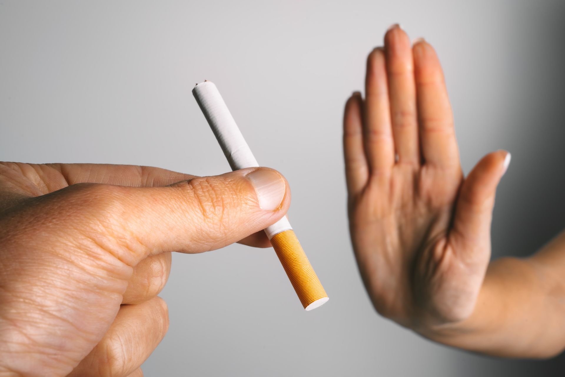 A hand is held up in front of a cigarette