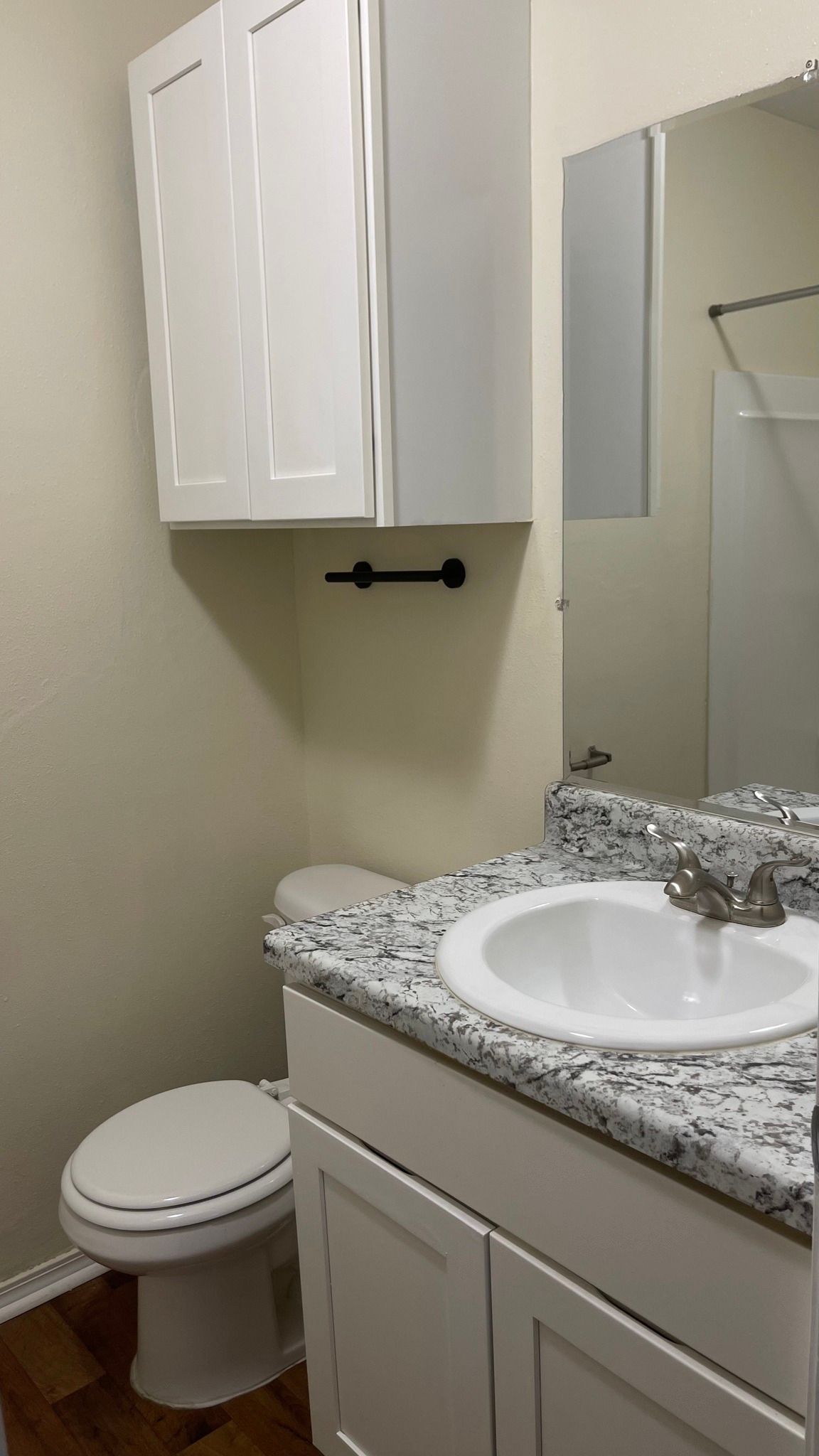 A bathroom with a sink , toilet and mirror.