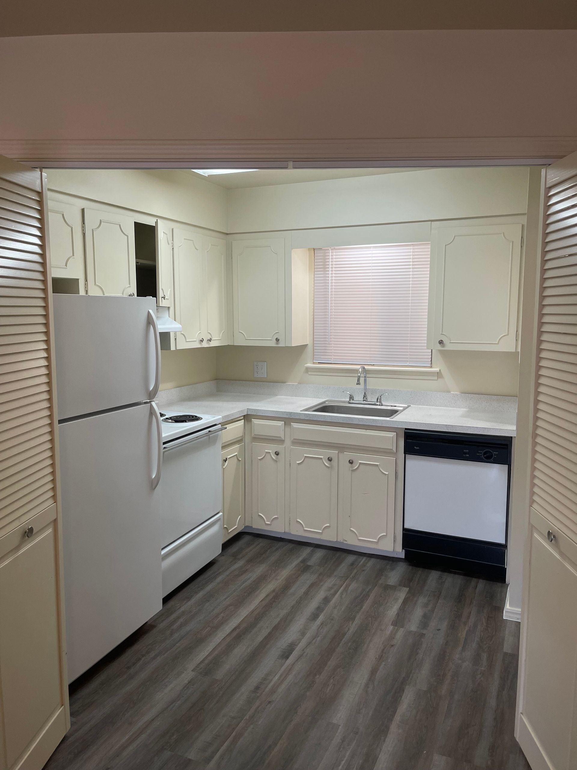 A kitchen with white cabinets , a refrigerator , stove , sink and dishwasher.