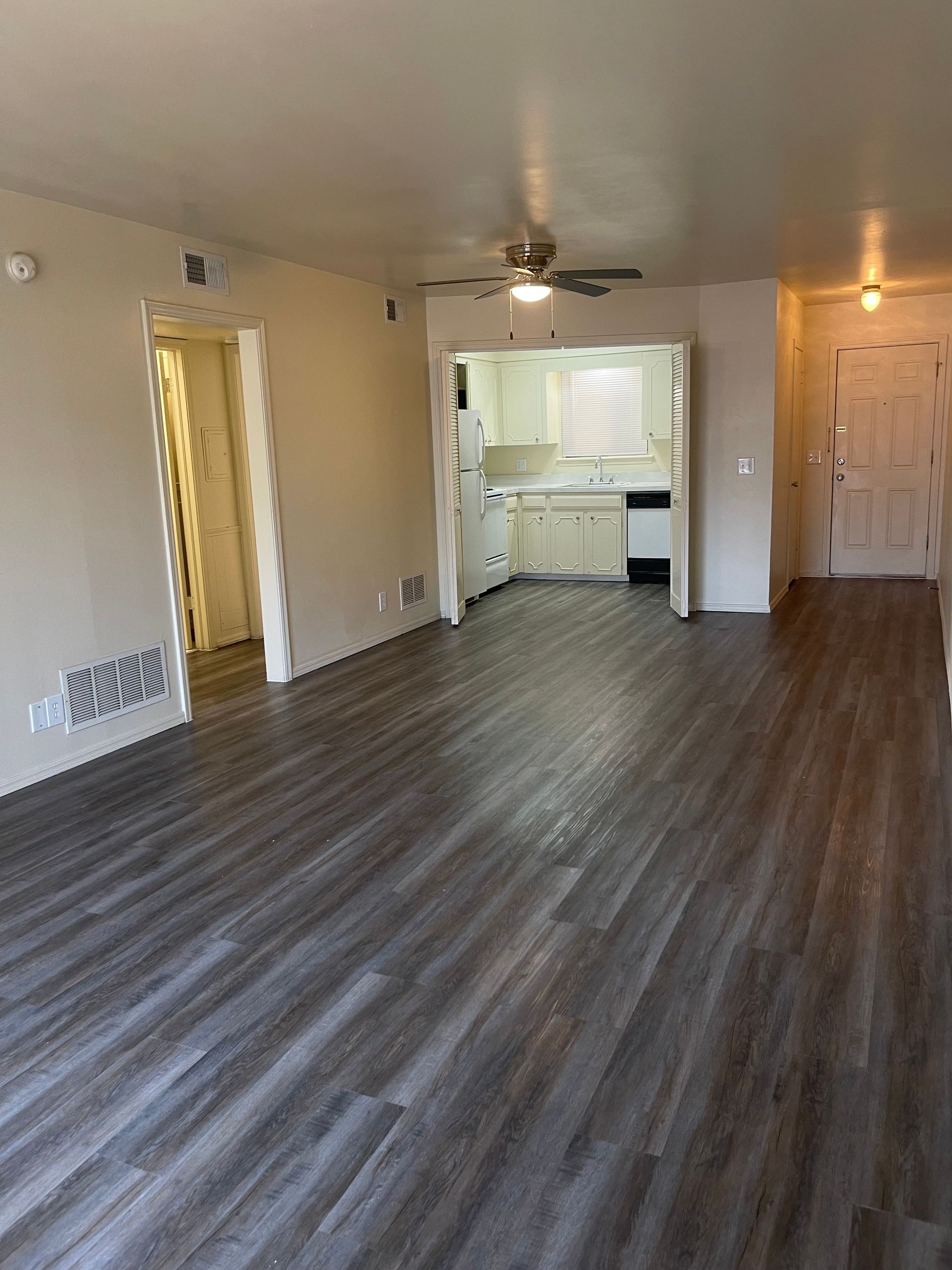 An empty living room with hardwood floors and a ceiling fan.