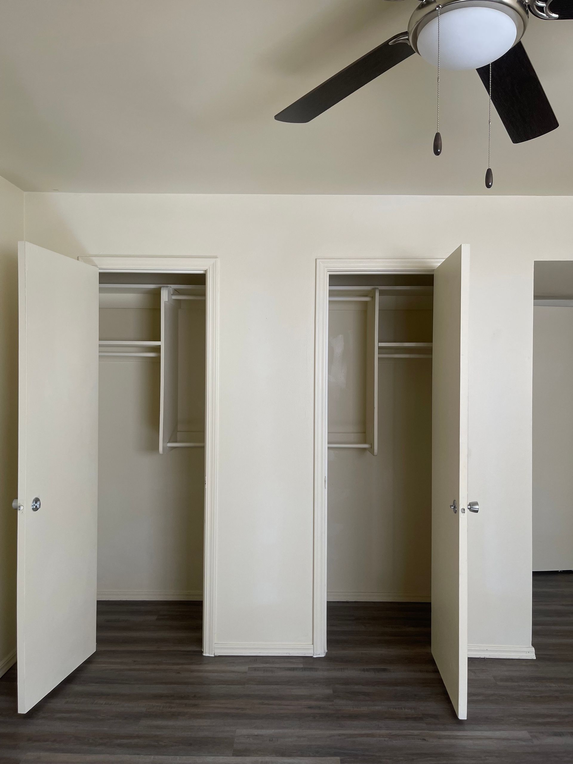 An empty closet with a ceiling fan above it