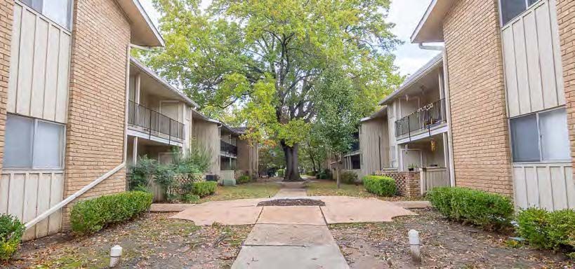 A brick apartment building with a tree in the middle of the courtyard.