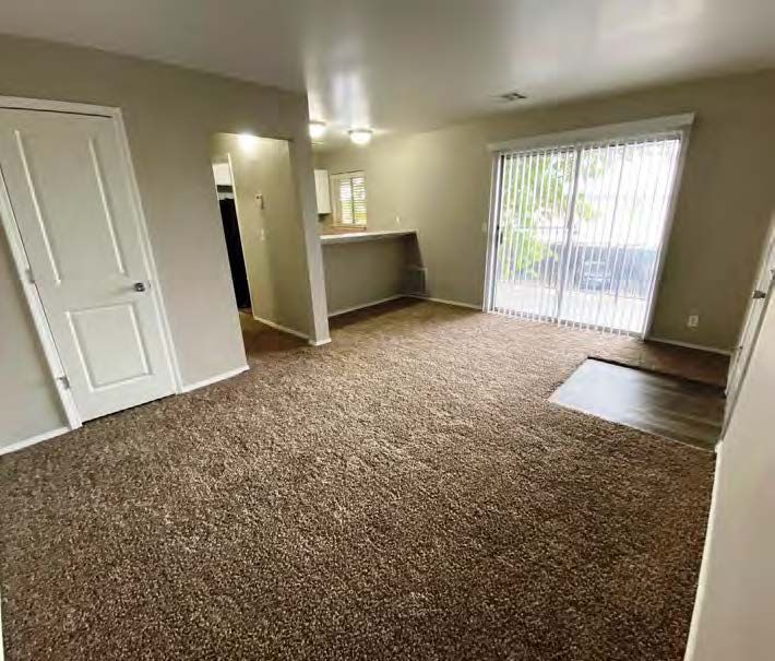 A living room with a sliding glass door and a brown carpet.