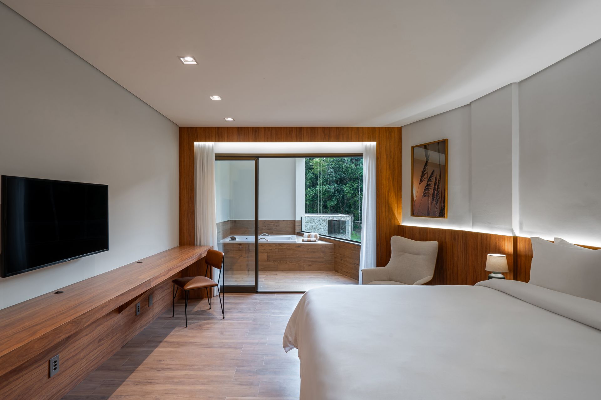 Um quarto de hotel com uma cama king size, televisão, escrivaninha e cadeira.