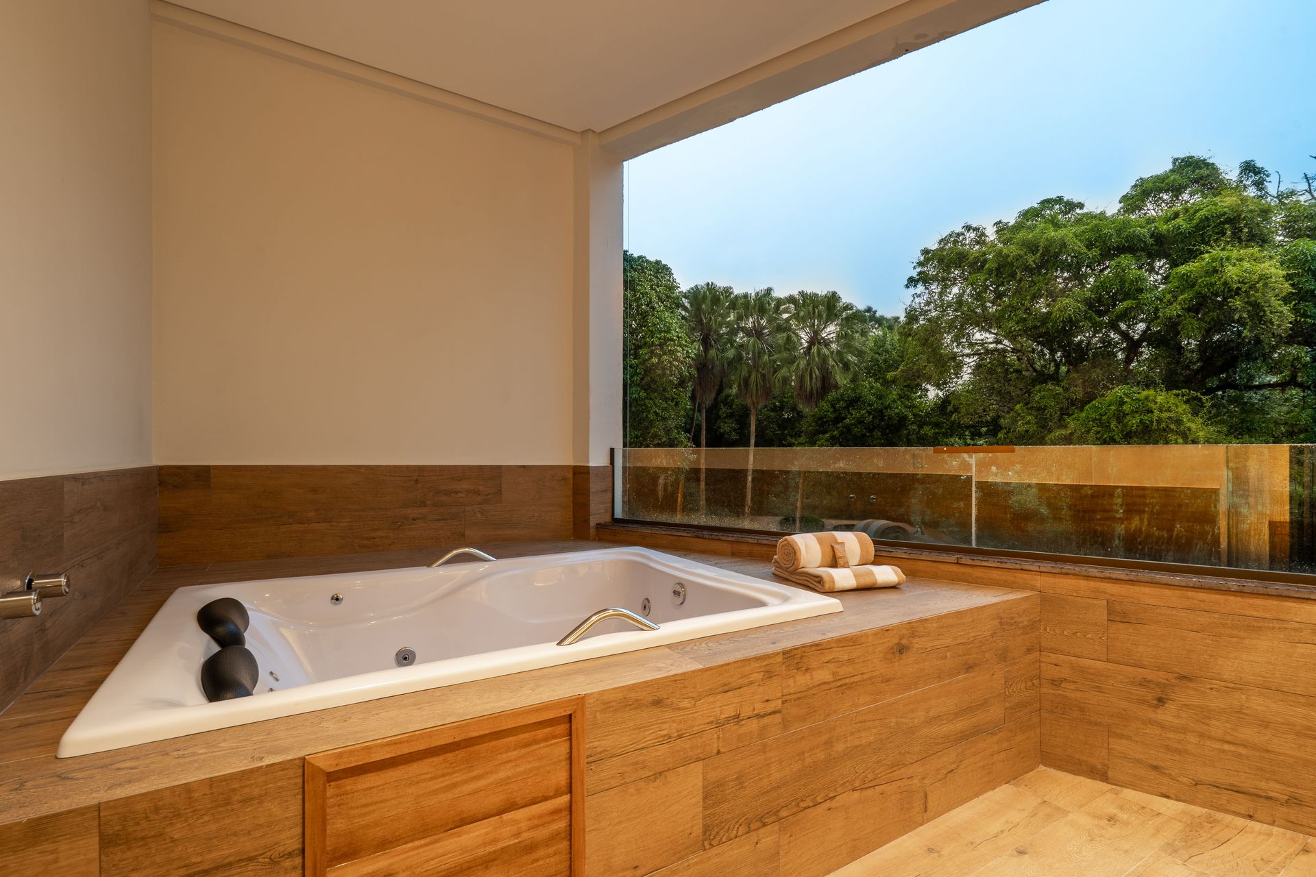 Um banheiro com banheira de hidromassagem e uma grande janela.