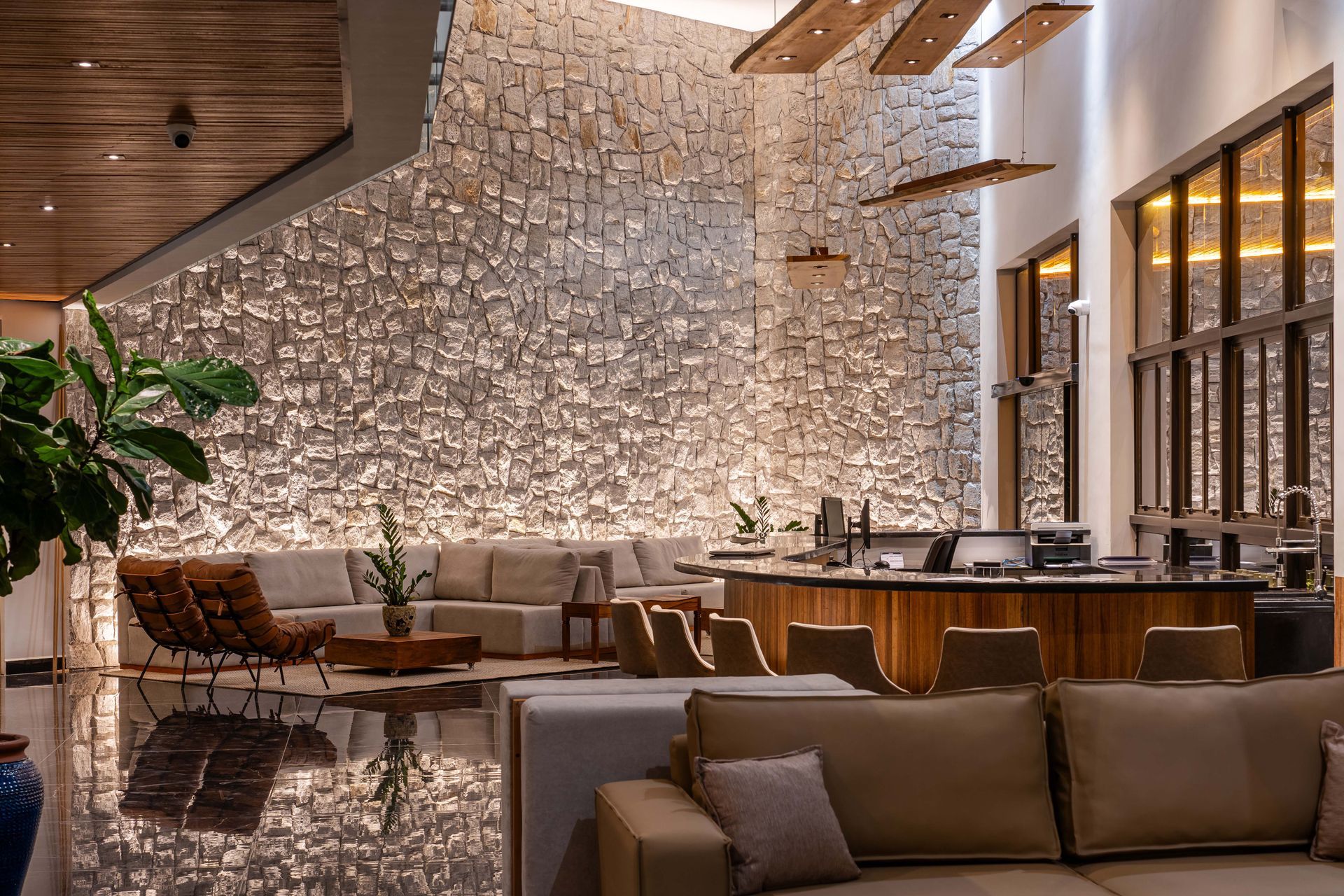 Uma sala de estar com um sofá, cadeiras e uma parede de pedra.