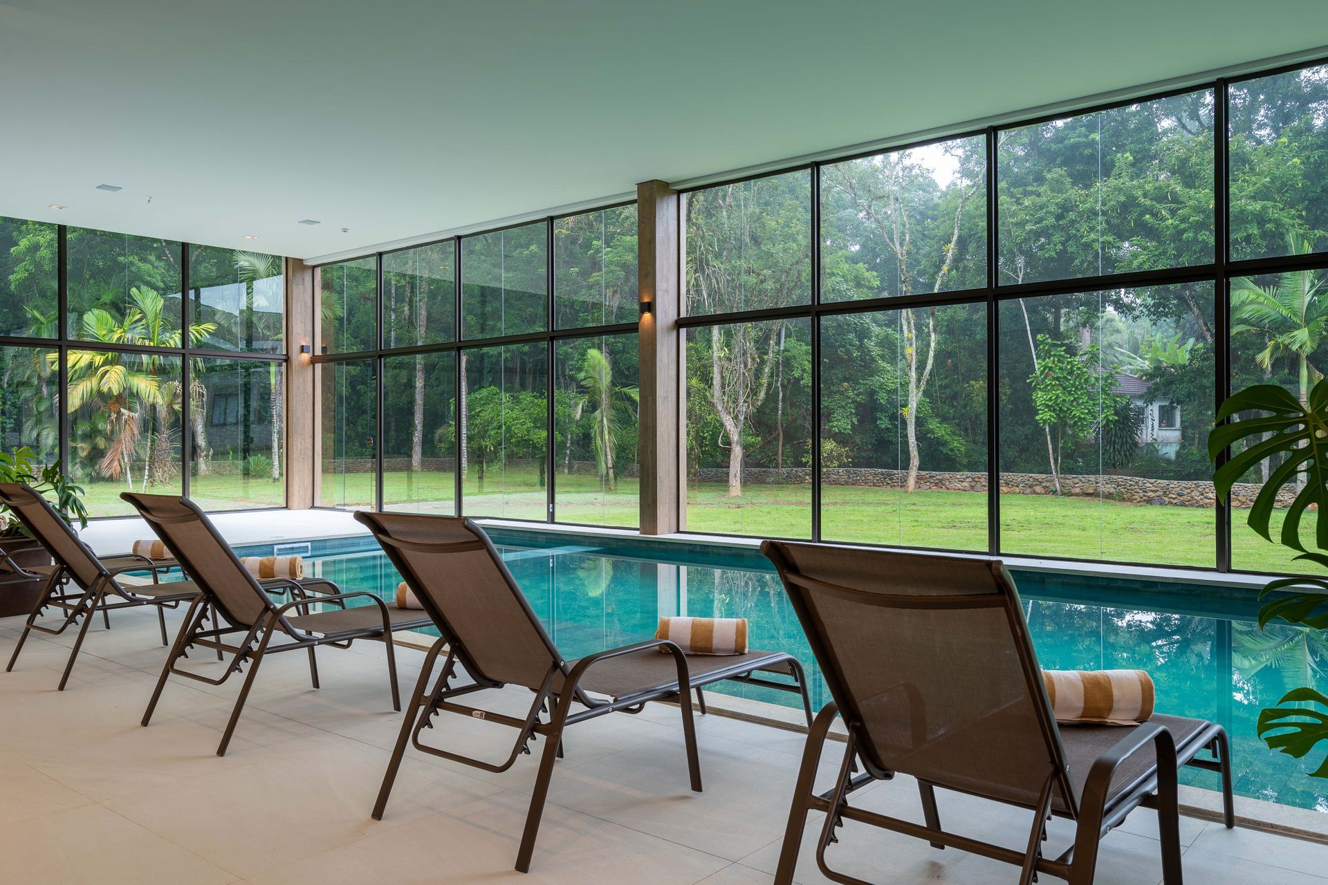 Uma fileira de espreguiçadeiras ao lado de uma grande piscina coberta.