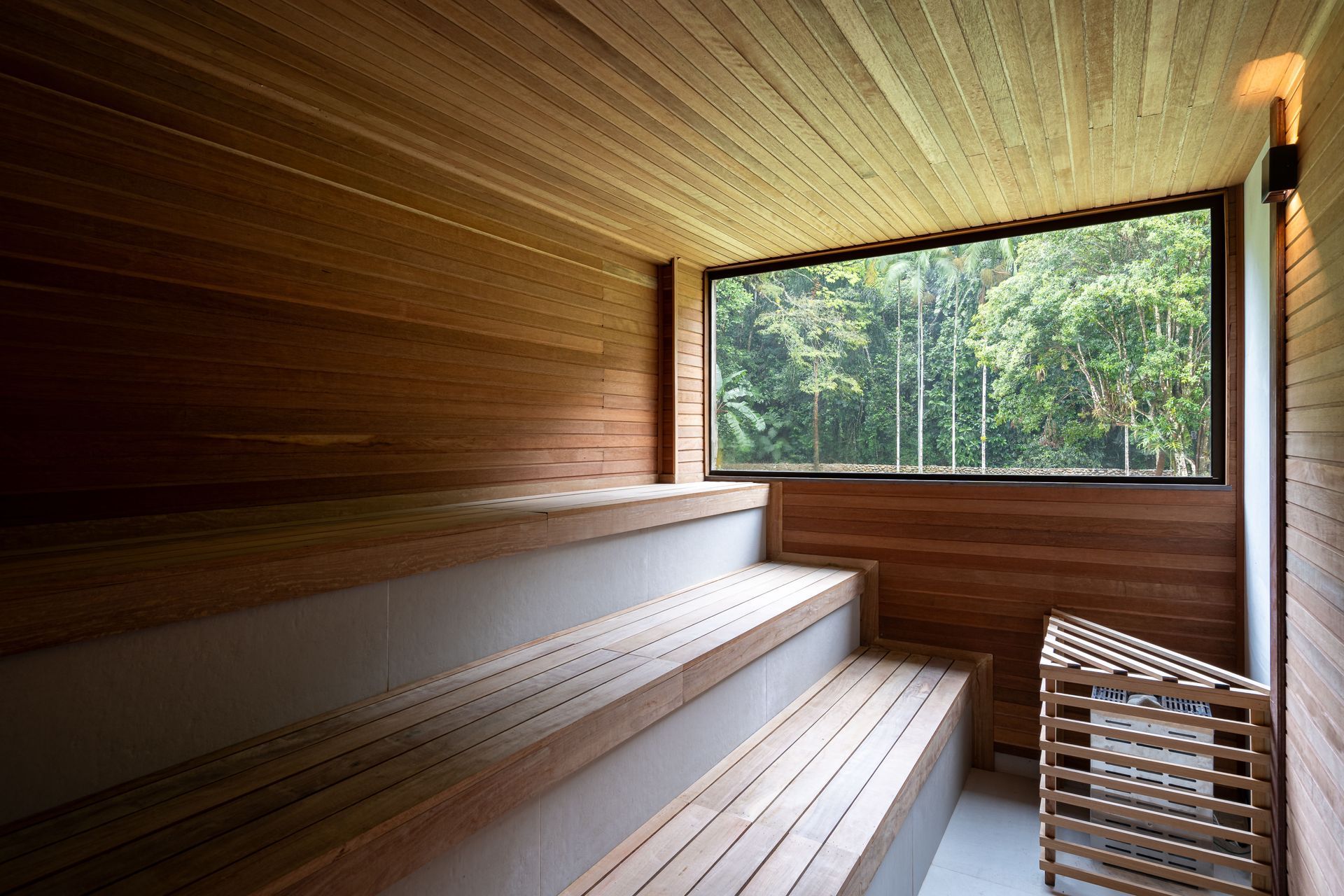 Uma sauna de madeira com uma grande janela com vista para uma floresta.