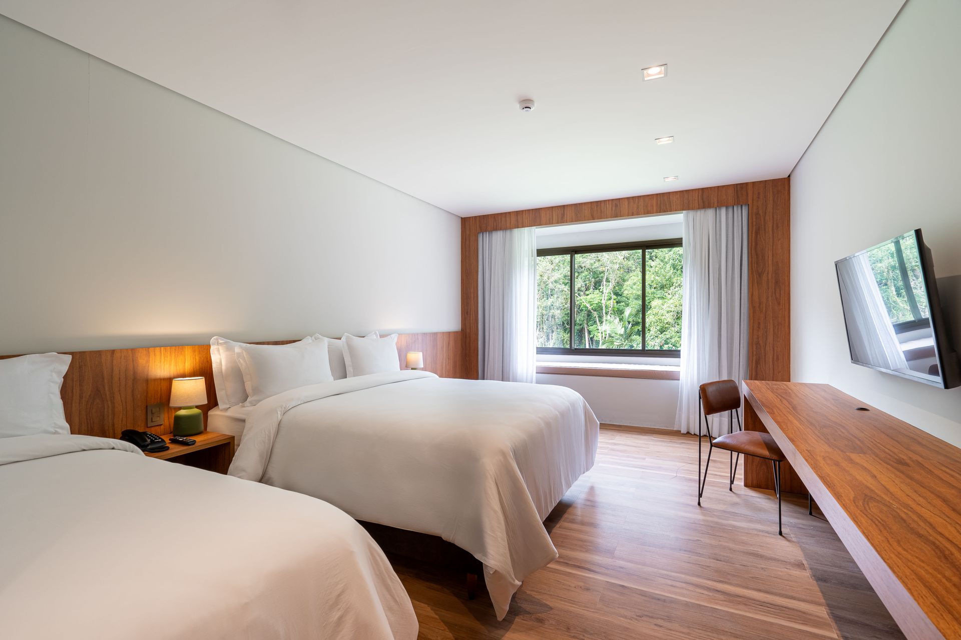 Um quarto de hotel com duas camas, uma escrivaninha e uma televisão.