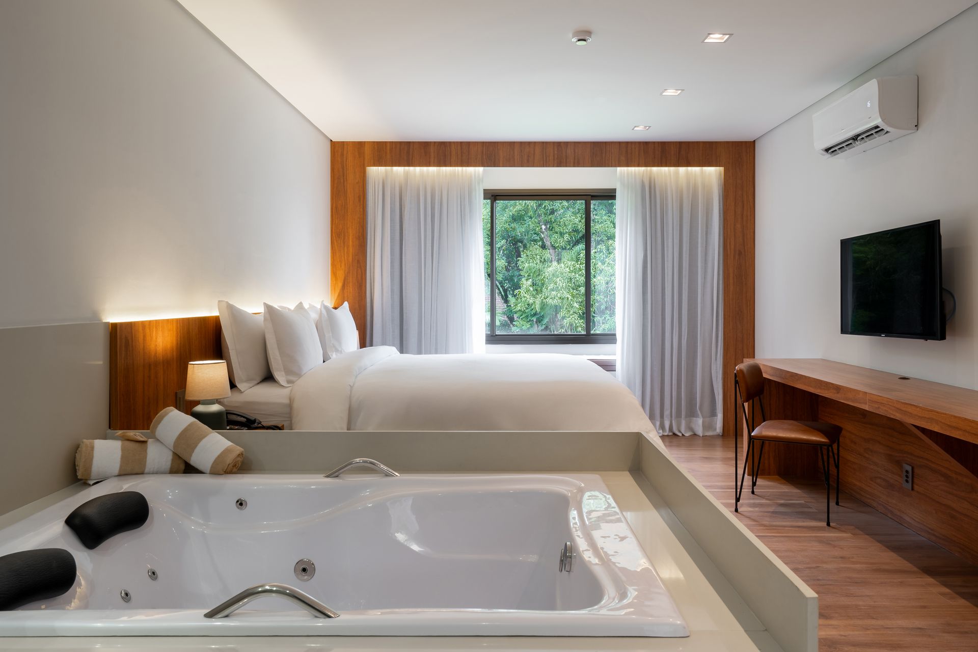 Um quarto de hotel com uma banheira de hidromassagem no meio.