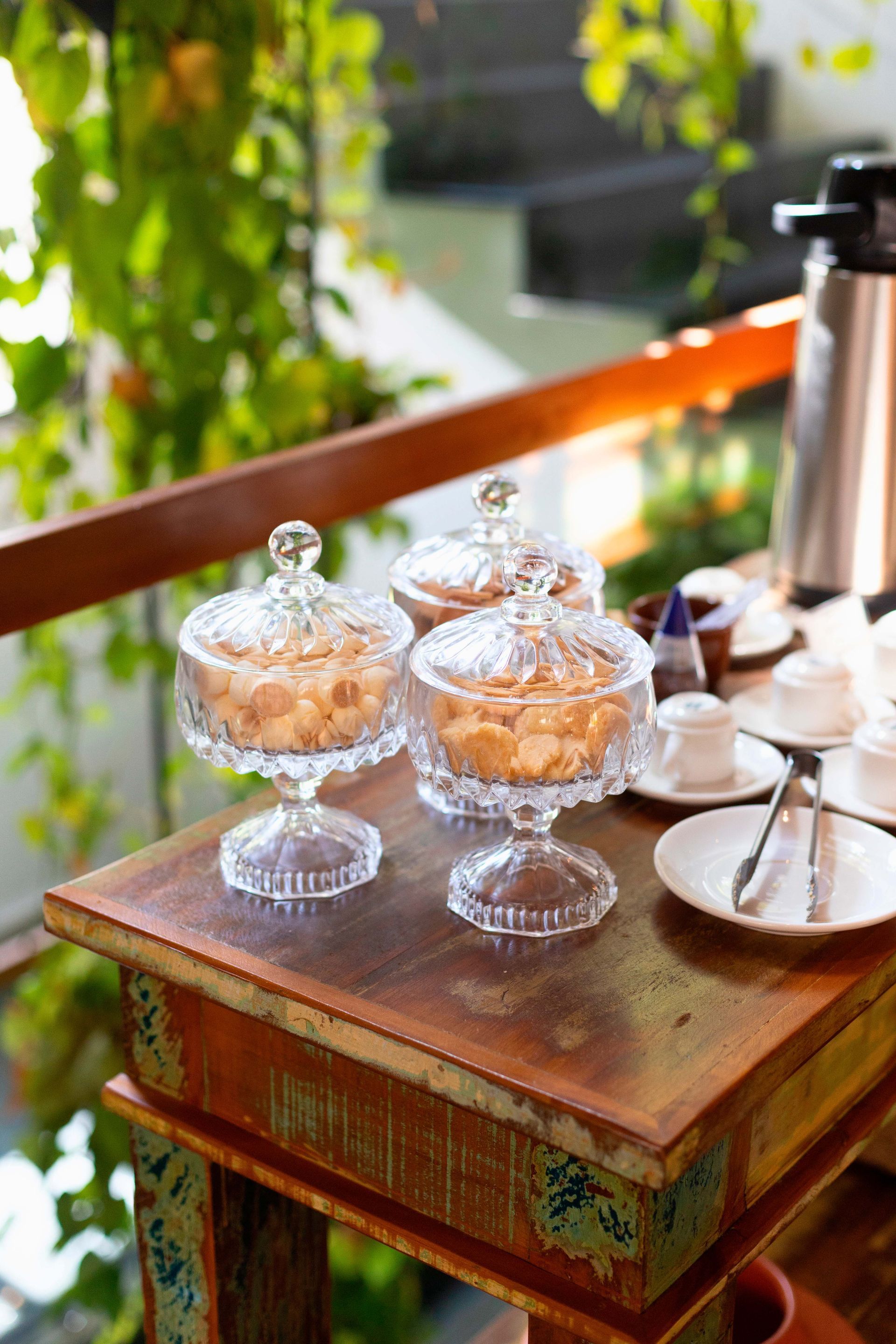 Uma mesa de madeira com três potes de vidro cheios de biscoitos.