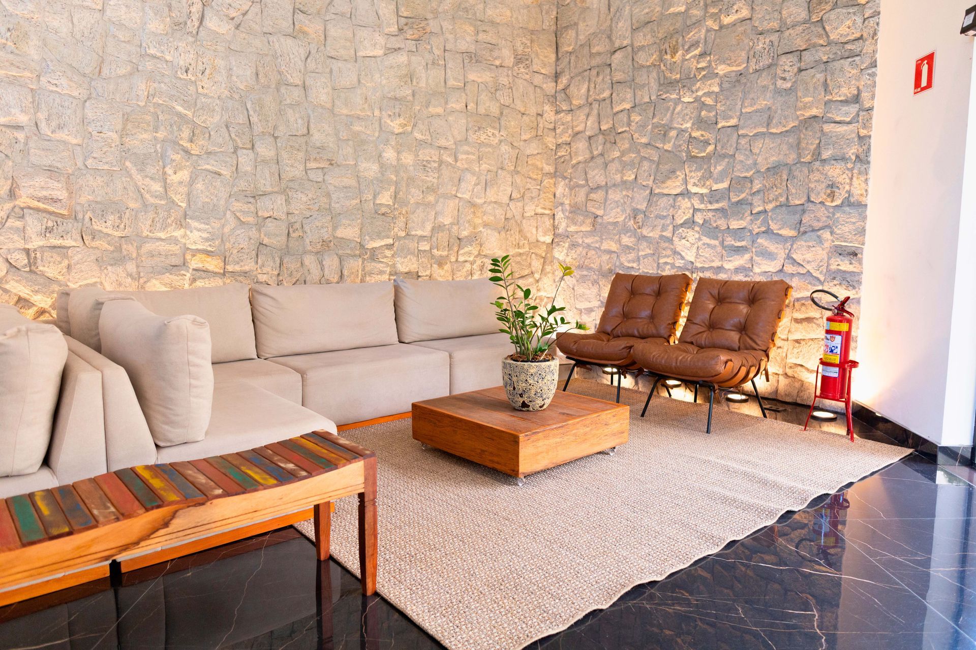 Uma sala de estar com um sofá, cadeiras, uma mesa e um extintor de incêndio.