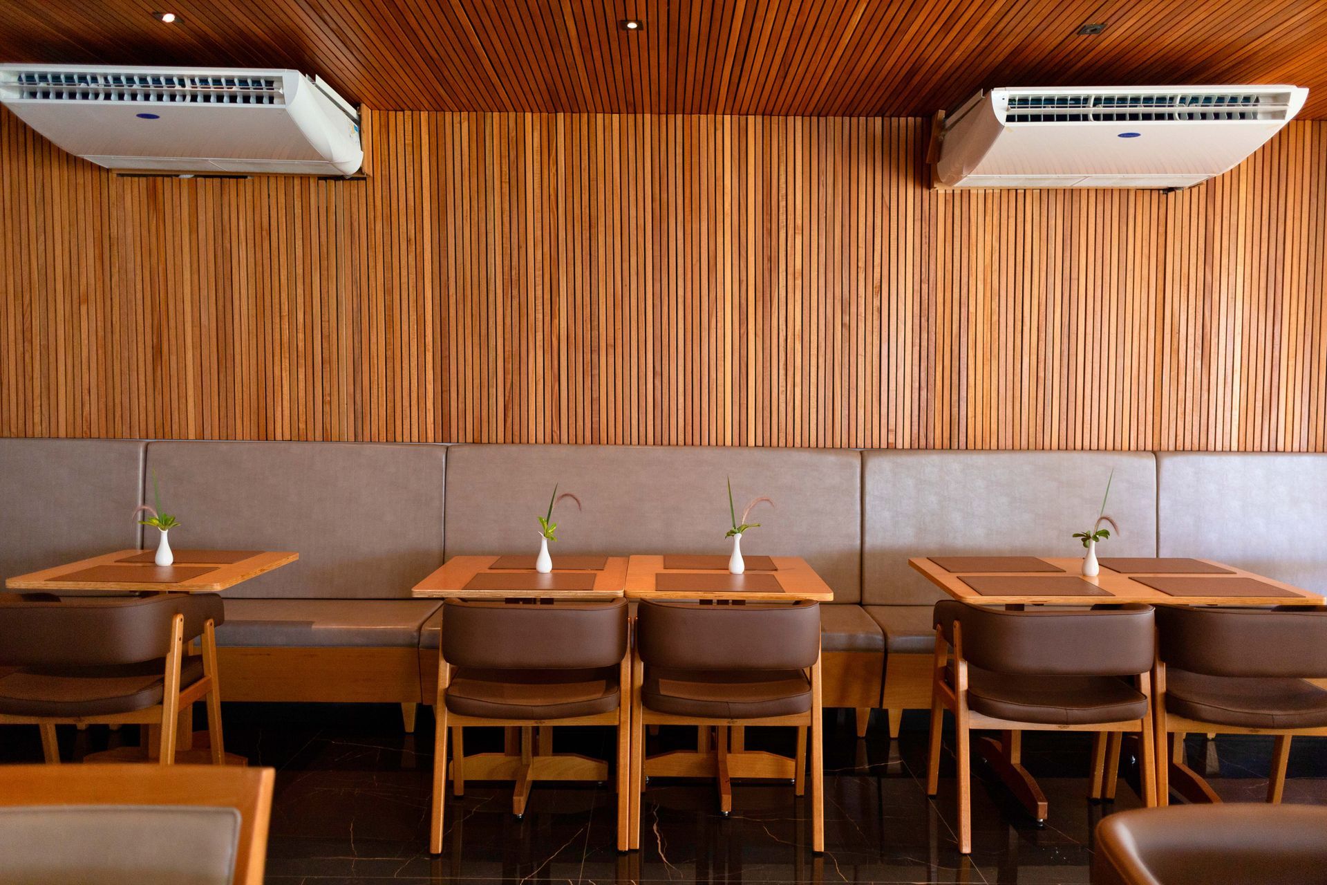 Um restaurante com mesas e cadeiras e uma parede de madeira