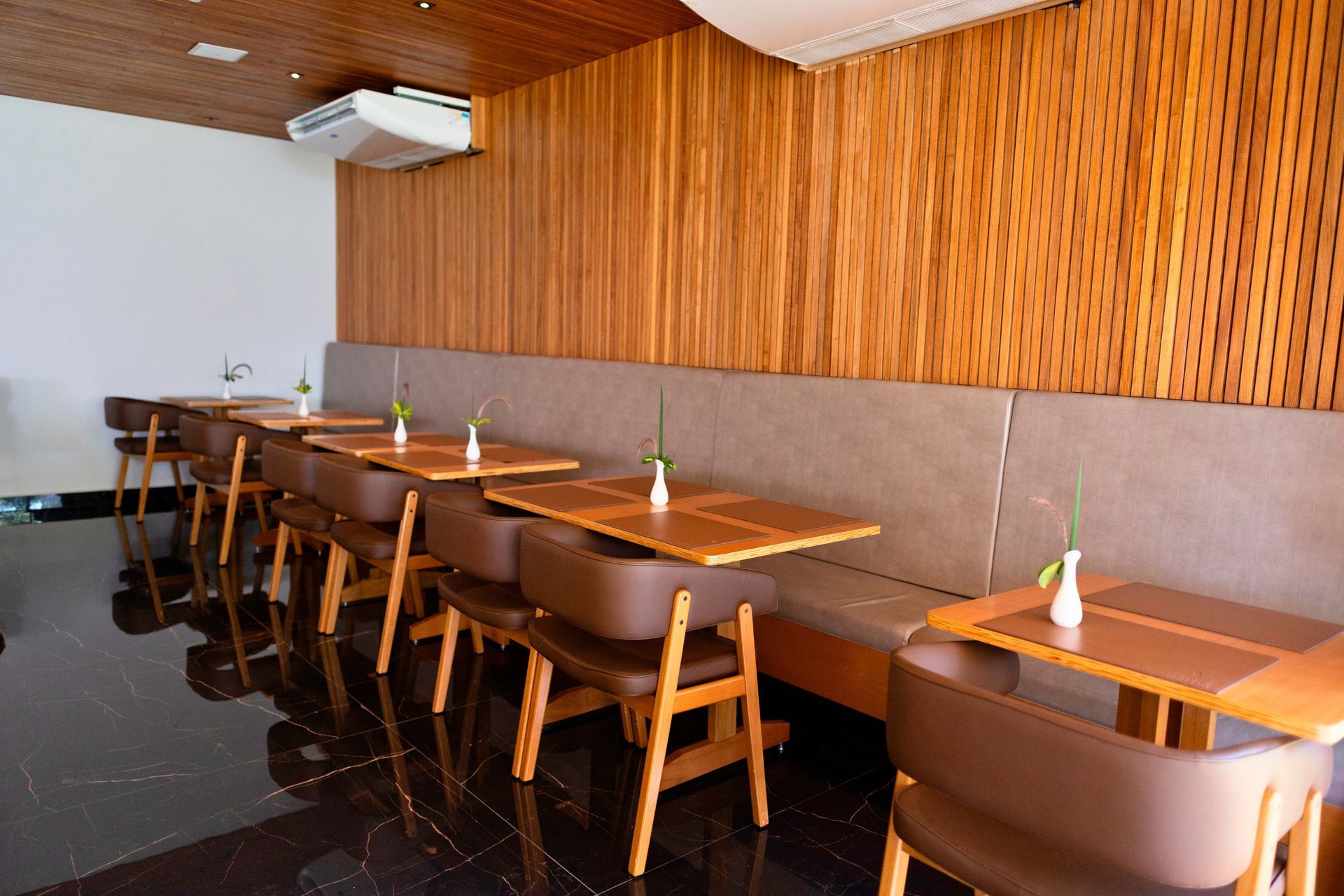 Um restaurante com mesas e cadeiras e uma parede de madeira.