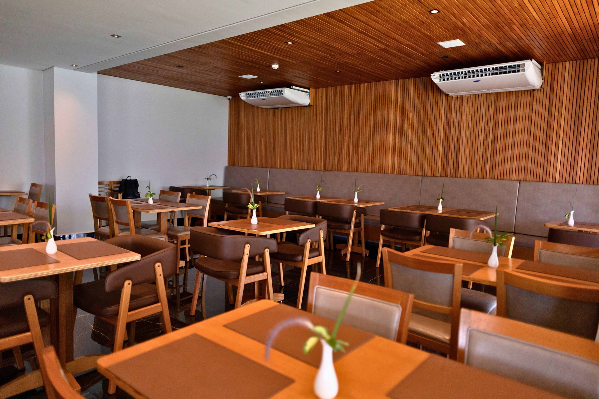 Um restaurante com mesas e cadeiras e um teto de madeira