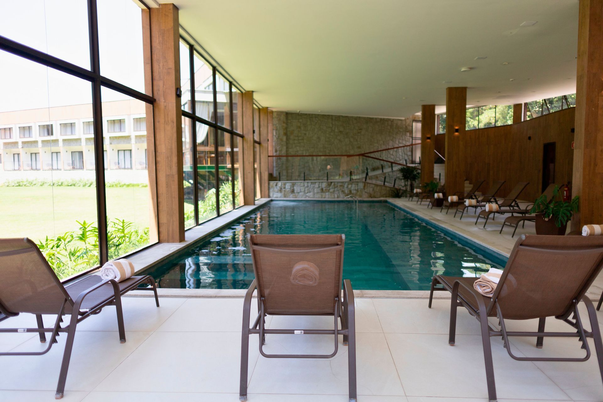 Uma grande piscina coberta com cadeiras e uma grande janela.