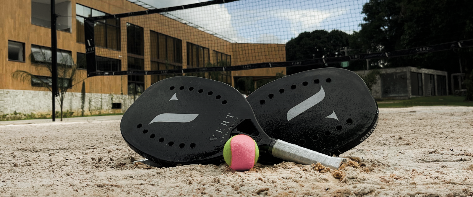 Um par de raquetes de tênis de praia e uma bola estão na areia.