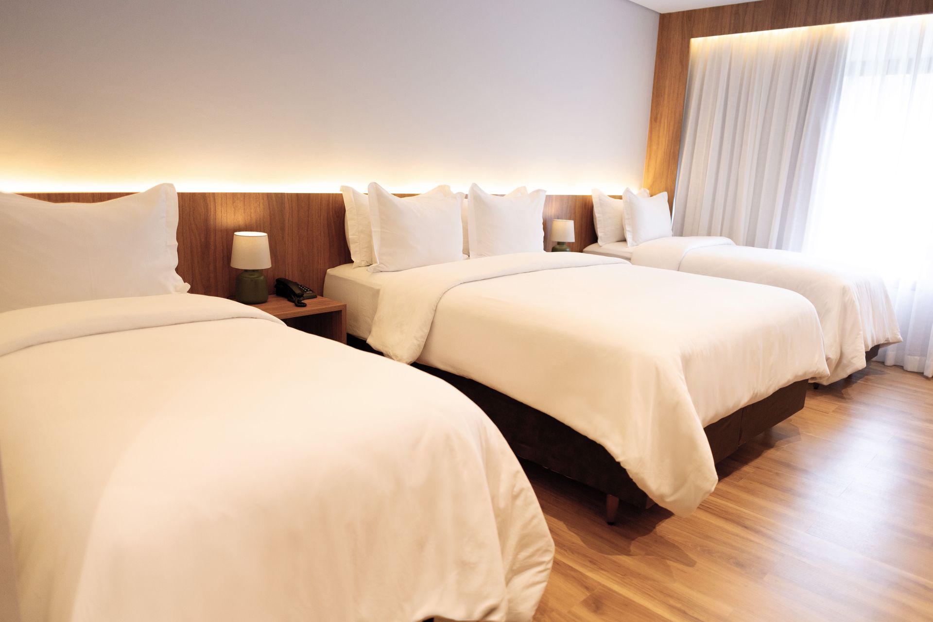 Um quarto de hotel com três camas e uma janela.