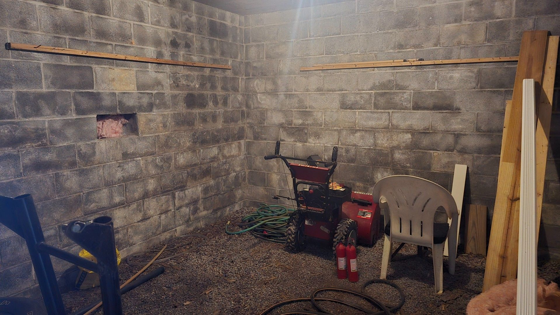 Basement room with concrete block walls, gravel floor, chair, and equipment.