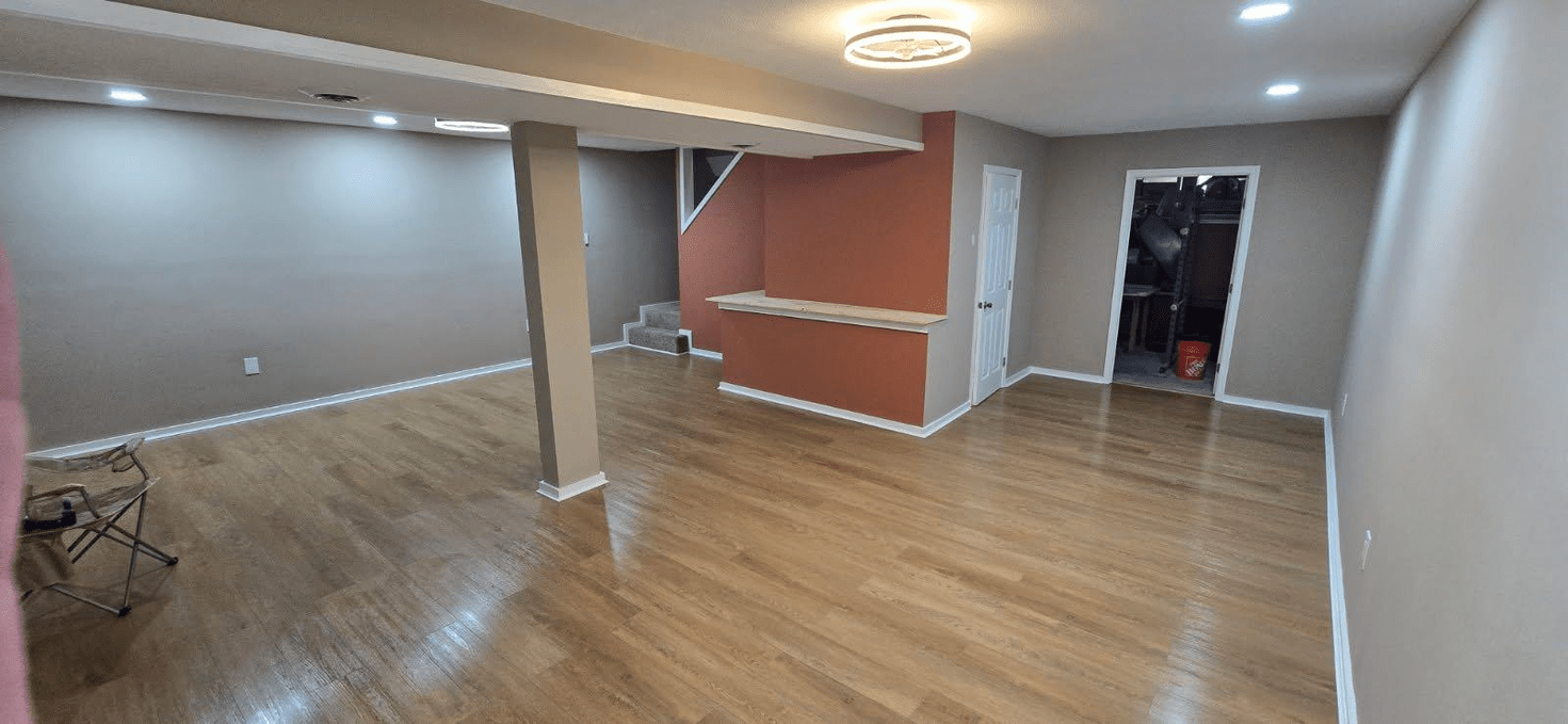A large, empty room with hardwood floors, gray walls, and a red-painted section.