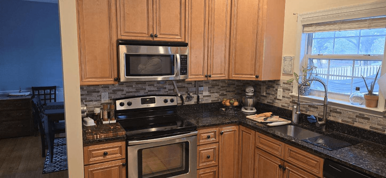 Kitchen with wooden cabinets, stainless steel appliances, and a window.